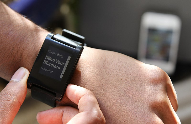 A user pressing a button on the sidle of a Pebble watch